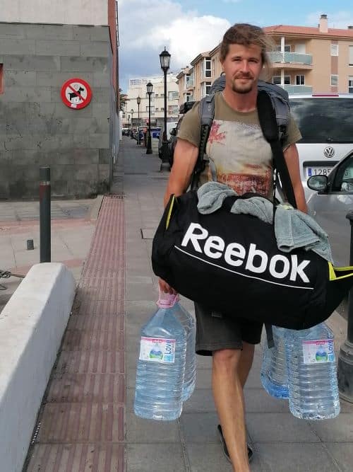 Roman vollgepackt mit 4 großen Wasserflaschen und einer riesigen Tasche mit unserer gewaschenen Wäsche