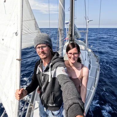 Anita und Roman am Bug ihres Segelboots am offenen Meer