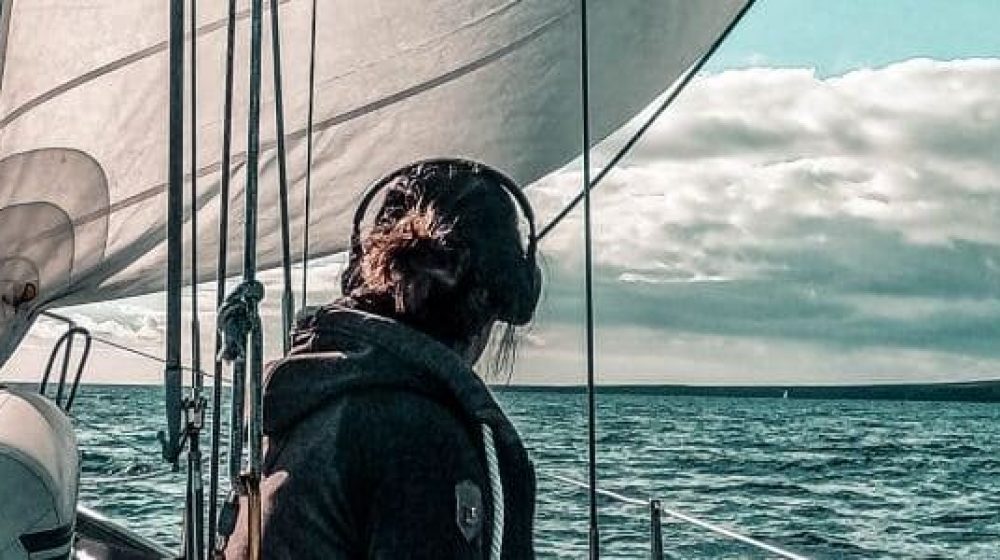 Anita sitzt am Segelboot und schaut zum Horizont