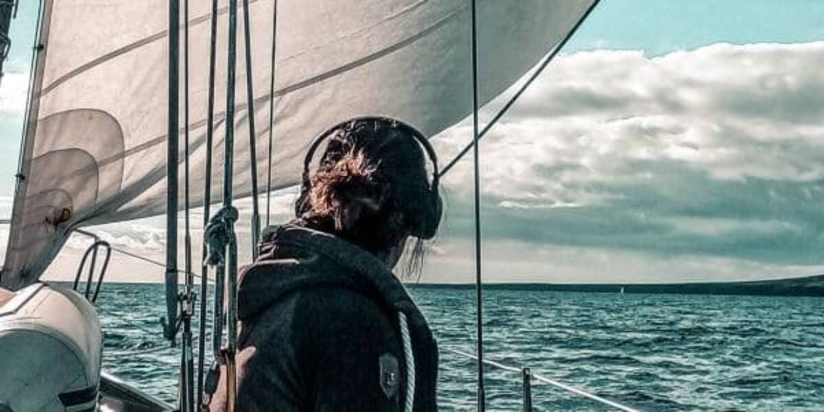Anita sitzt am Segelboot und schaut zum Horizont